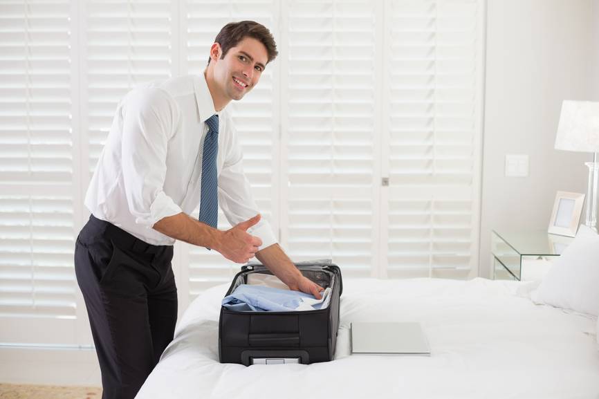 Un homme met une chemise pliée dans une valise