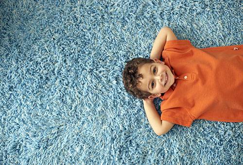 Le garçon est allongé sur un tapis propre