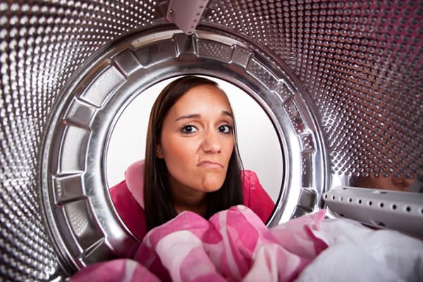 La fille regarde dans la machine à laver