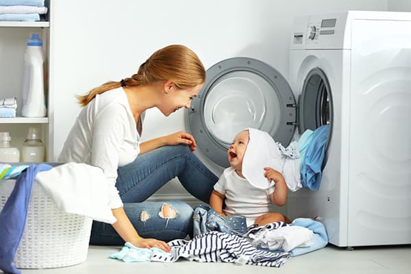 Mamma och barn tar isär kläder efter tvätt